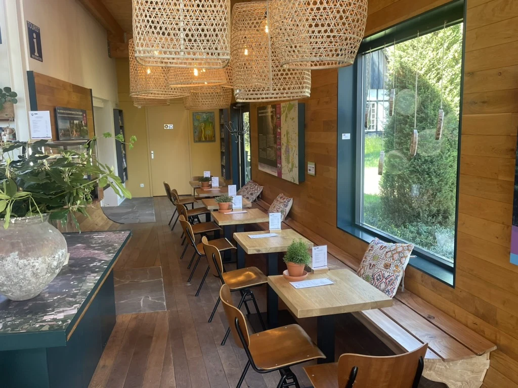 Het museumcafé met houten wand, rotan lampen en grote ramen